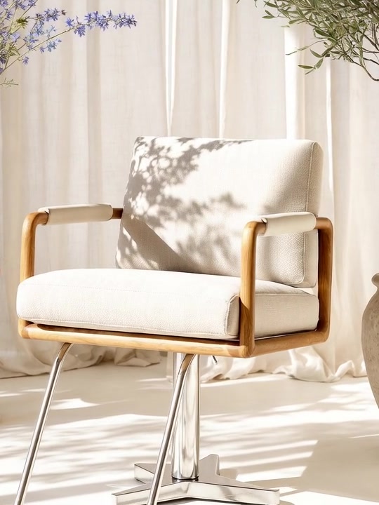 An oak and cream linen styling chair on a chrome base in soft sunlight